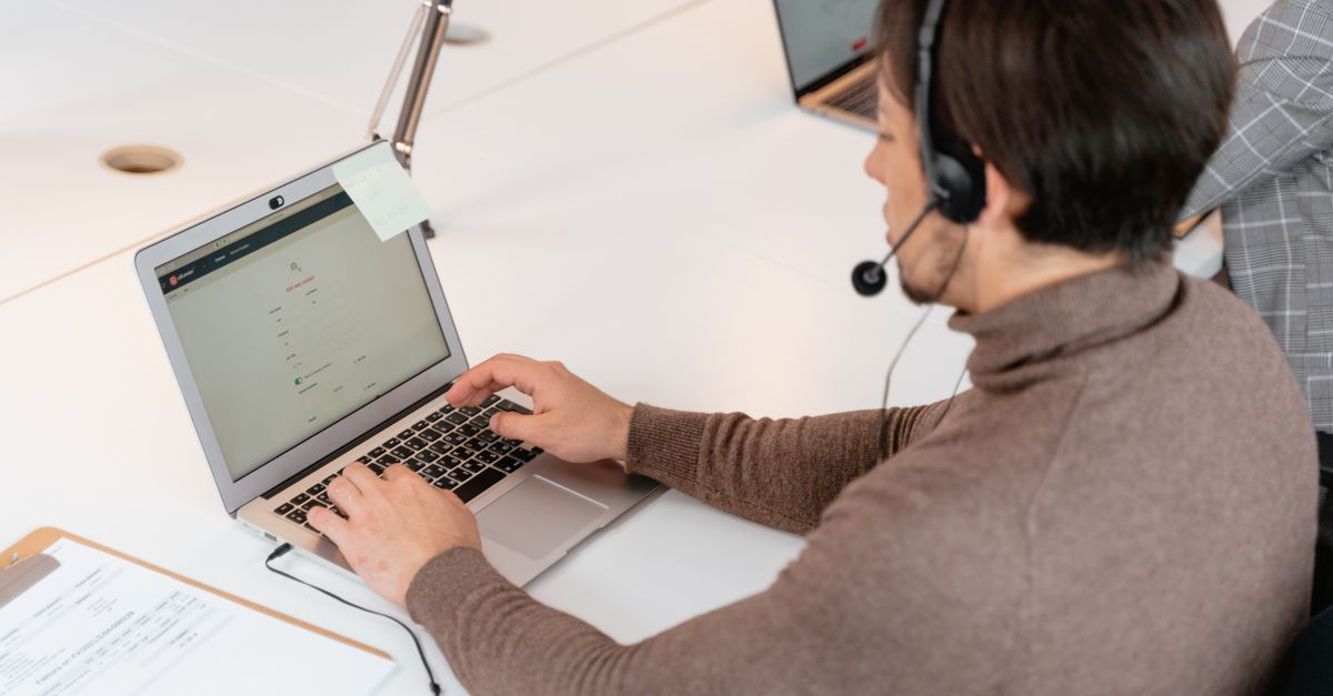 Support agent wearing a headset working on a laptop in an office